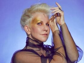 JoyceDiDonato poses with her hands before her face, looking directly at the camera.