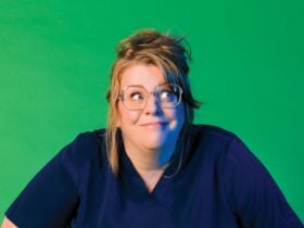 Georgie Carroll with messy hair wearing scrubs