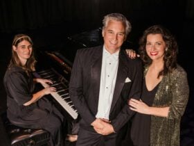 three people sit around a piano