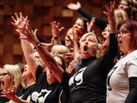 A group of people singing with their hands in the air