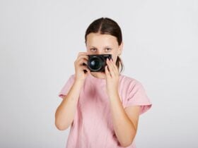 a teenaged girl holds a camera in front of her face