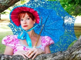WOman dressed in Jane Austen style costume leaning on a tree