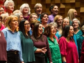 Choir of women singing passionately during an a cappella workshop.