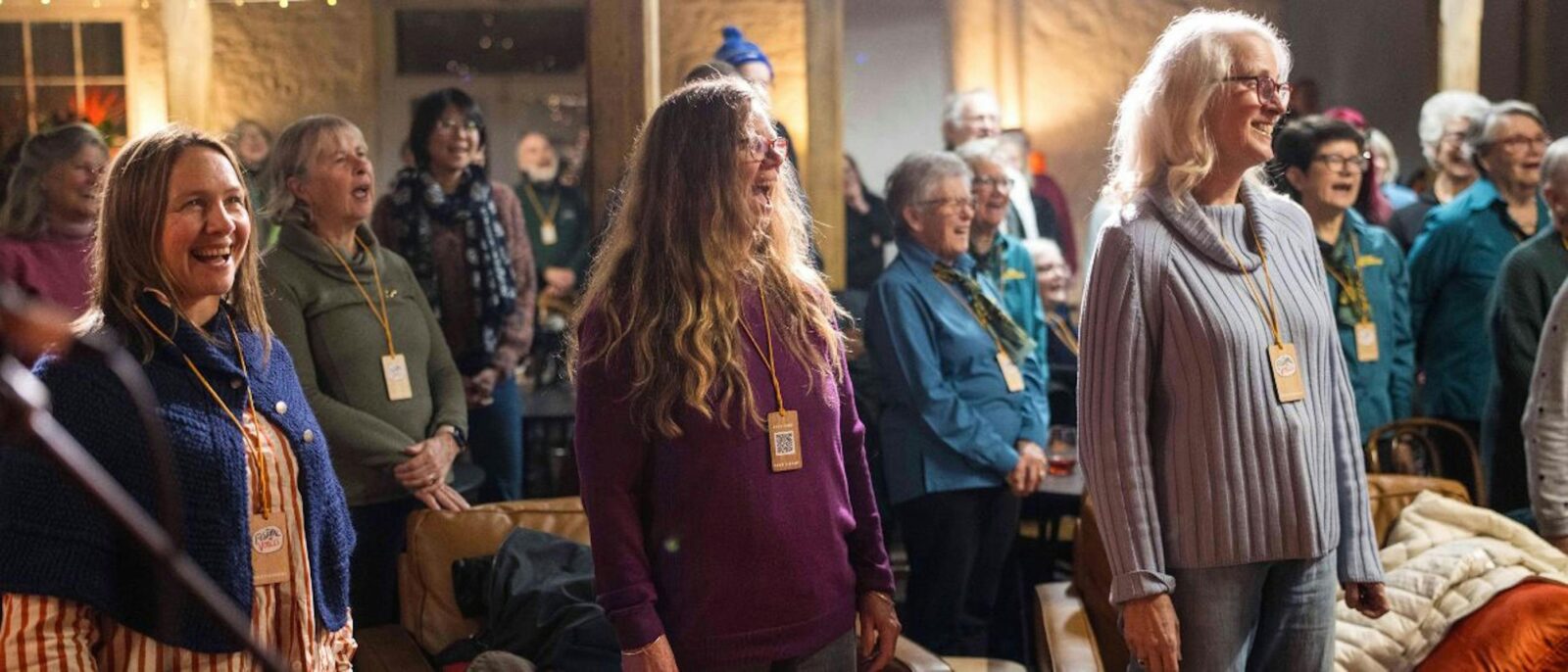 A group of people inside a hall smiling and singing