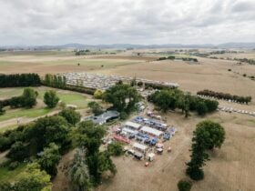Aerial photo pf green paddocks, tents, cars parked in neat rows