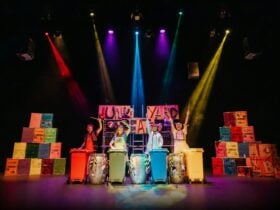 Four people drum on wheelie bins