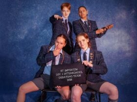 Four female and non binary actors dressed in drag as an elite high school male debating team