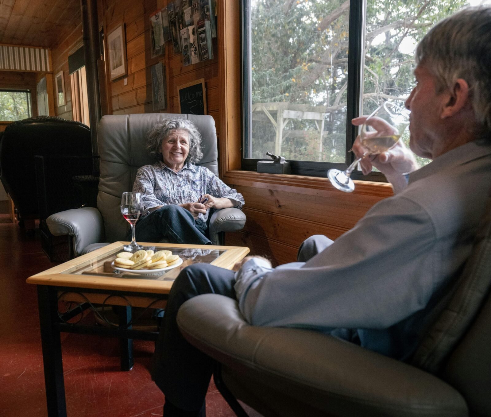 2 people sitting drinking wine with snacks on table