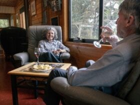 2 people sitting drinking wine with snacks on table