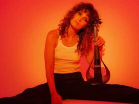 A woman sitting on the floor, holding a musical instrument, with bare feet.