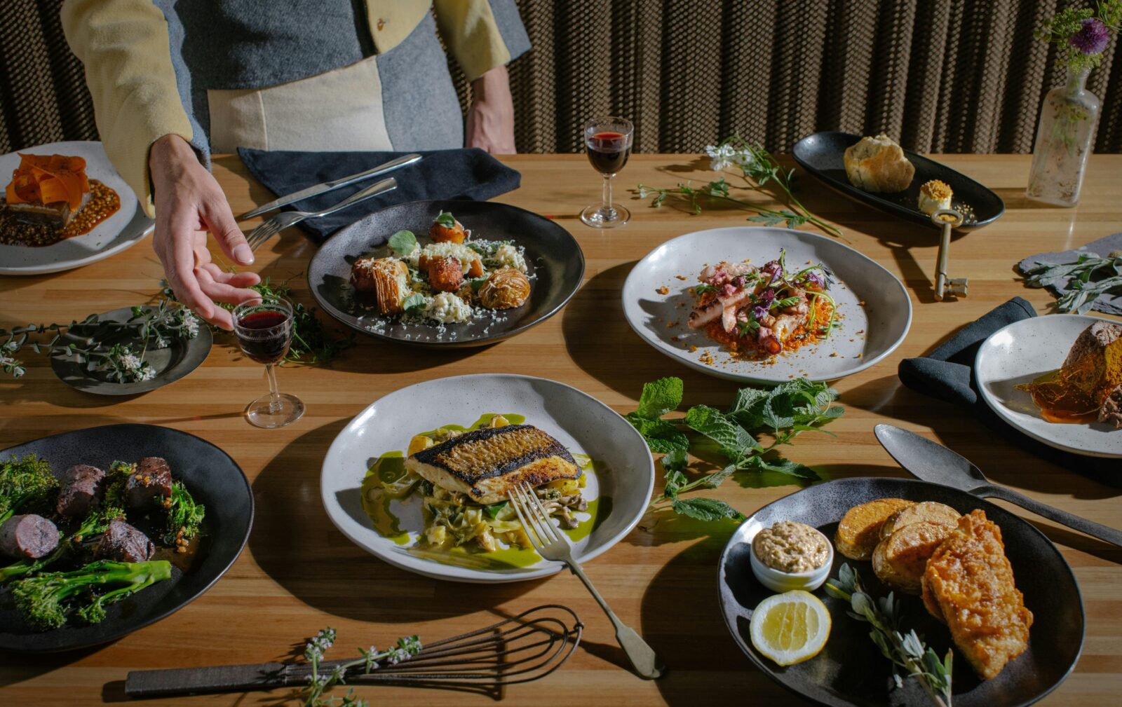 Person reaching for plated dishes on a dining table