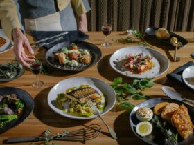 Person reaching for plated dishes on a dining table