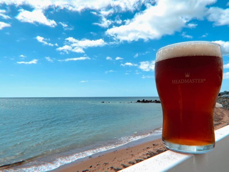 Beer on ledge whilst over looking blue ocean