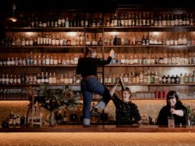 Cocktail bar, three female bartenders making drinks infront of a large backbar - gin and whisky