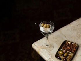 Martini on table next to plate of olives and nuts