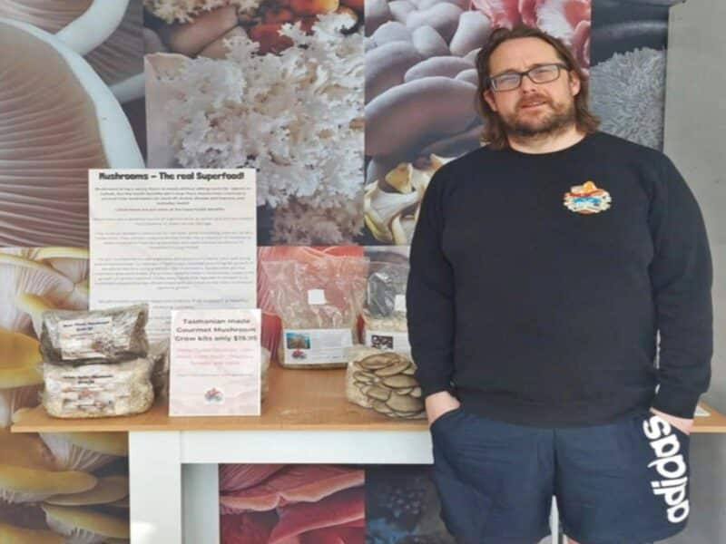 Table with mushroom grow kits with a man in a black jumper standing to the right