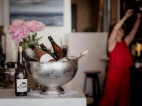 Sommelier reaching for wine with cold wine on ice in the forground on the bar with fresh peonies