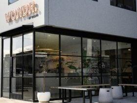 Outdoor seating at a modern cafe featuring floor to ceiling windows creating a sleek entrance.