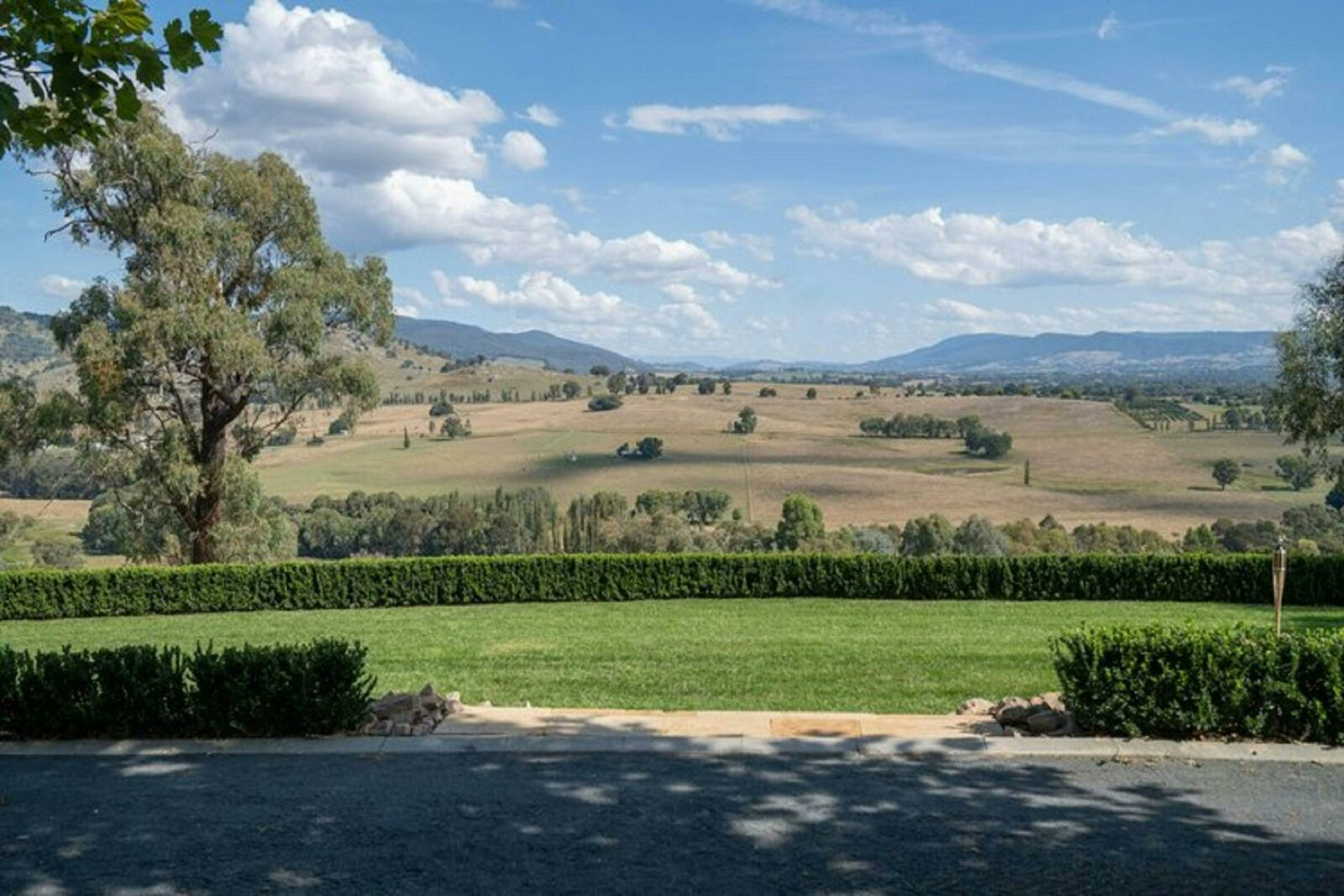 View overlooking green lawns with the mountains in the background. The sky is blue with clouds