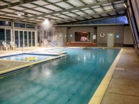 A spacious indoor heated pool and spa complex with steam rising from the water.