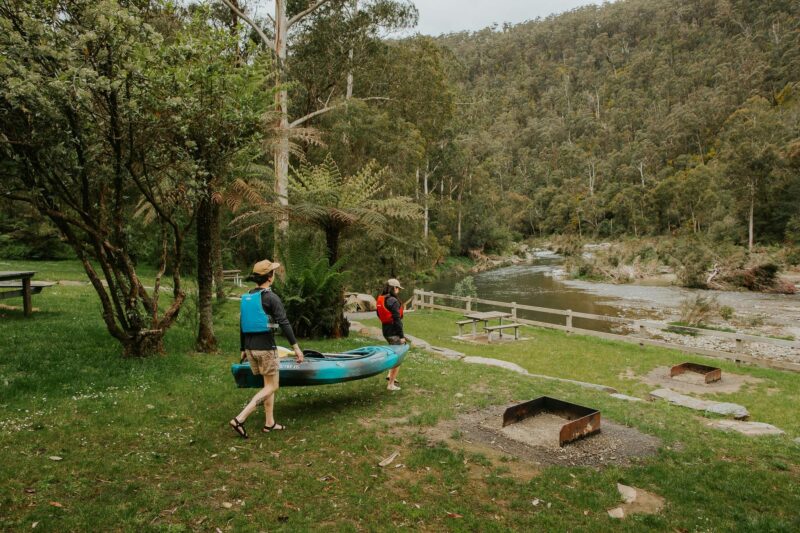 Two people carrying canoe towards river