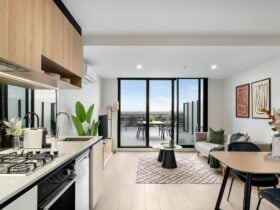 Modern living area with kitchen, dining table, chairs and couch. A balcony in the background.