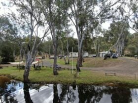 Lake in the foreground with vans, tents and vehicles in the background