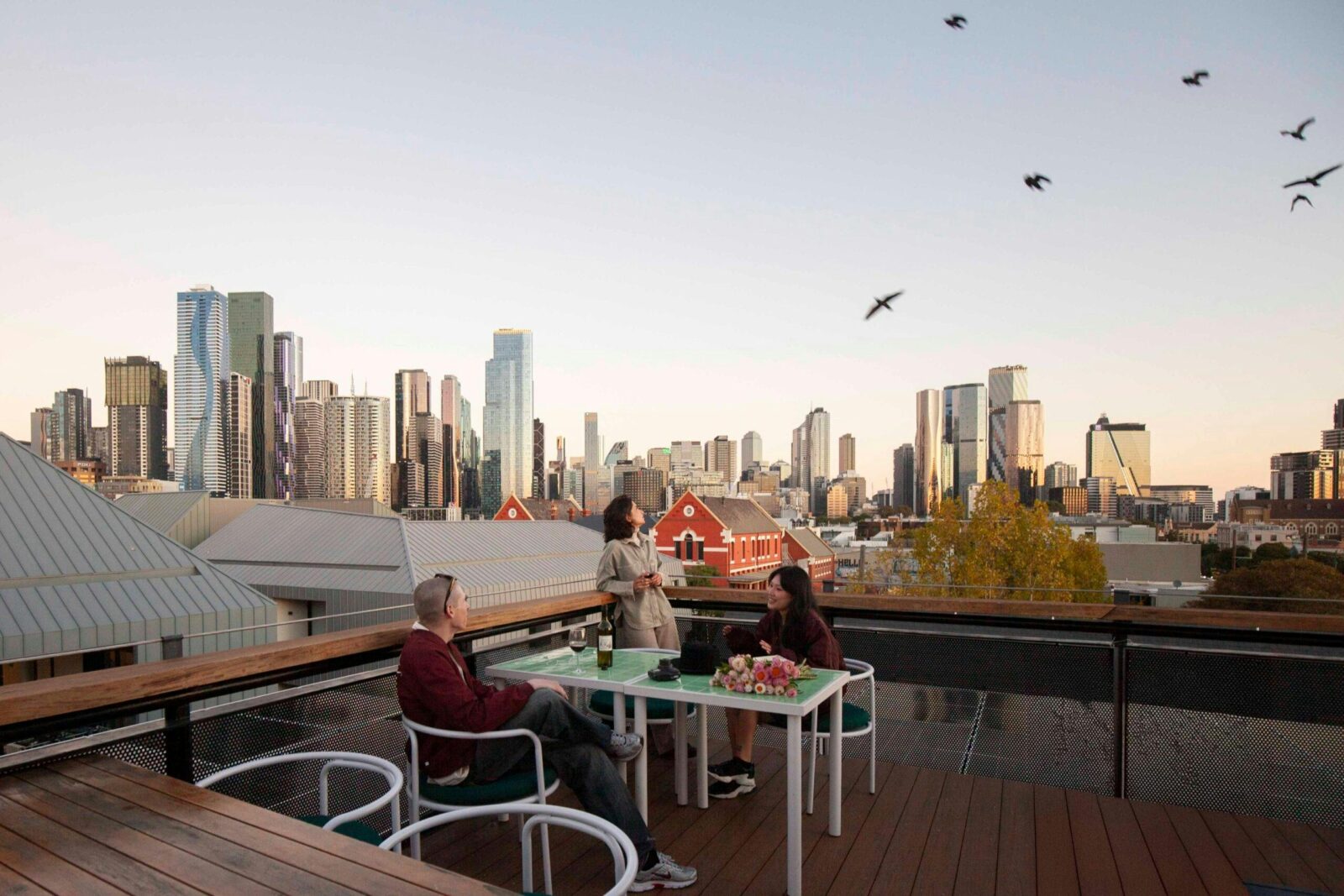 three people on the terrace with the city skyline in the background