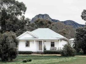Exterior of a white country home with a mountain in the background