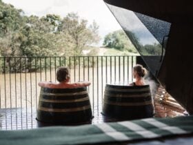 Man and woman bathing in hot springs barrels on their private glamping deck overlooking nature