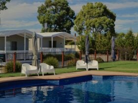 A blue swimming pool surrounded by a white fence