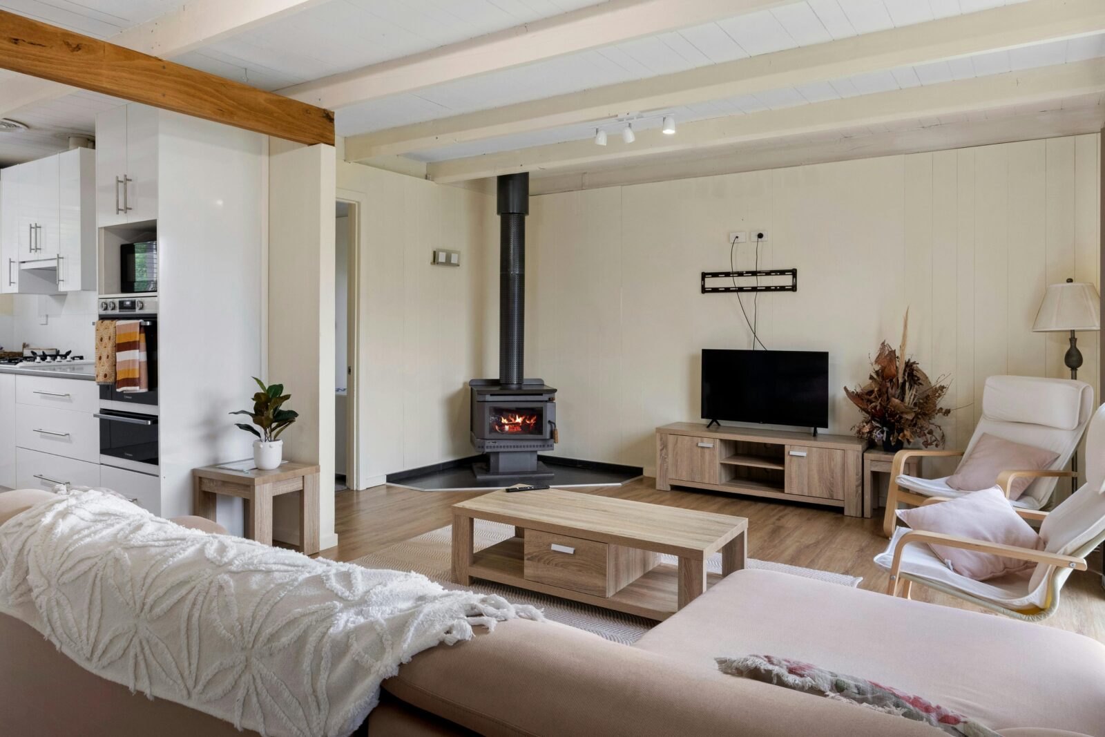 Image of living room from front door looking over couch to television and enclosed fireplace