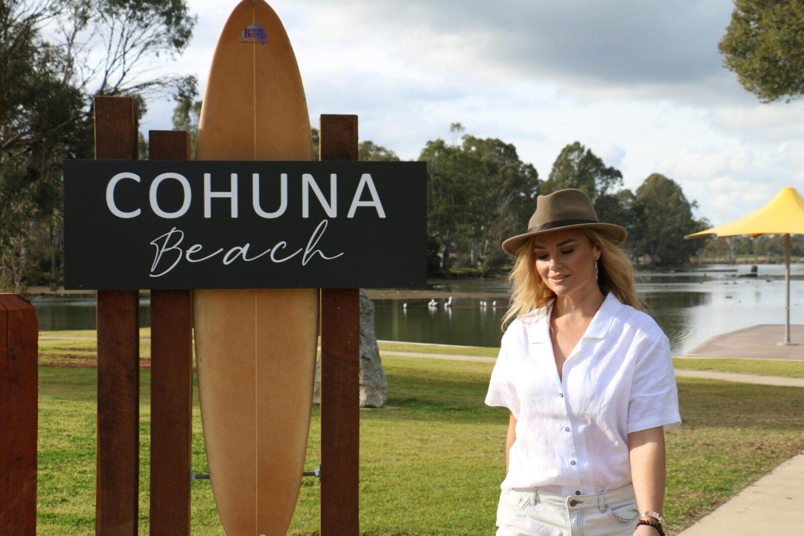 Woman in brimmed hat walking past Cohuna Beach sign