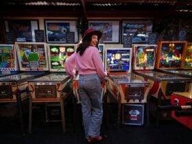 Person looking back over their shoulder and playing a row of pinball machines