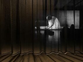 A photograph of crouched projected figure seen through a semi-sheer curtain