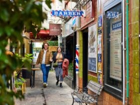 A young adult couple walking hand in hand down this small laneway looking at the surrounding shops
