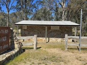 Stone building with wooden fence. Rustic sign saying Fosters Lake Rest Area built on a stone ledge