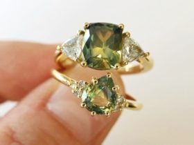 Two Sapphire and Diamond Yellow Gold Rings held against a pale cream background