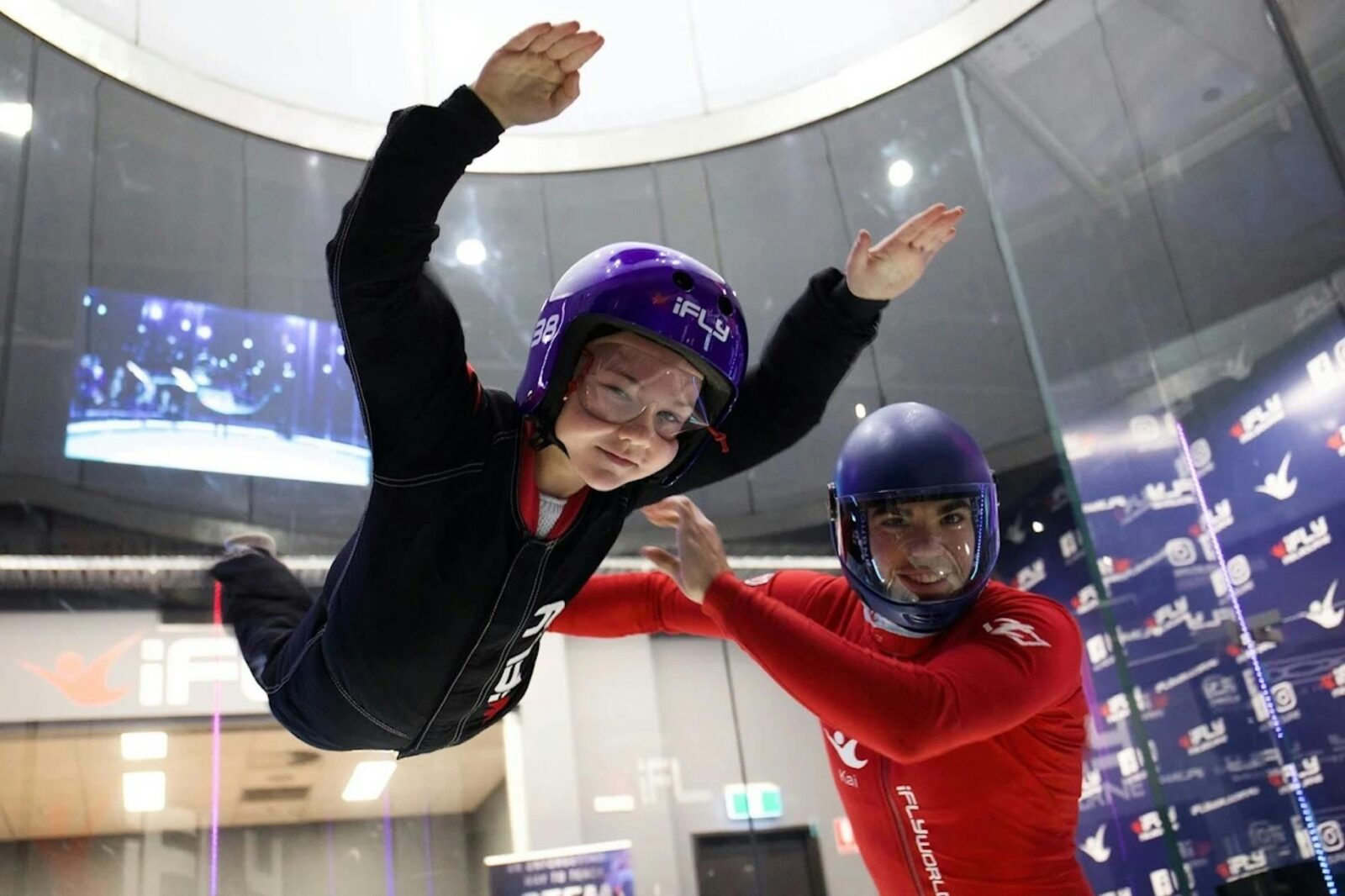 Young flyer supported by instructor during a family flight session at iFLY Melbourne.