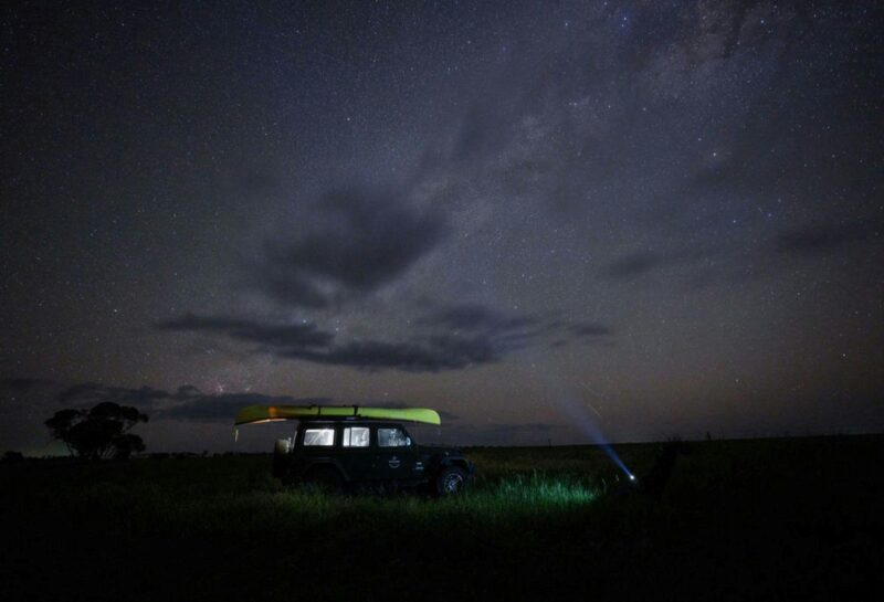 Small SUV with light on with the night sky as a backdrop