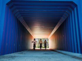 Three cyclists riding through a tunnel painted with blue stripes