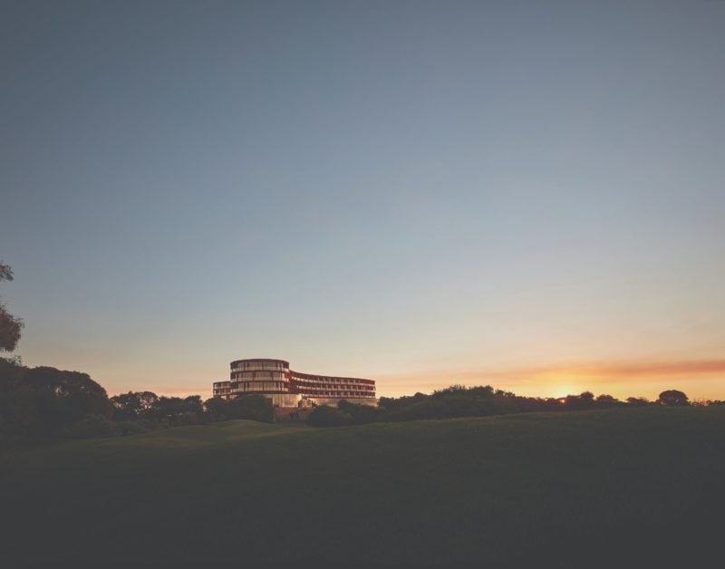 Wide angle view of RACV Cape Schanck Resort silhoutted in the sunset blue and orange hues.