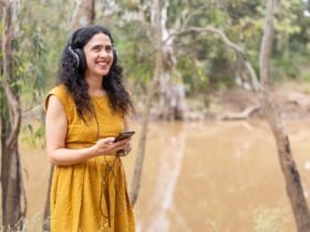 River Whispers - person with headphones and holding a mobile phone