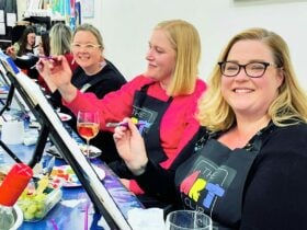Women at a paint and sip event enjoying painting a canvas