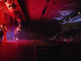 A circus has a person suspended in the air on the Forge Theatre stage. The audience is onlooking.