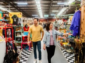 man and woman walking along aisle of shop with colourful clothing and accessories