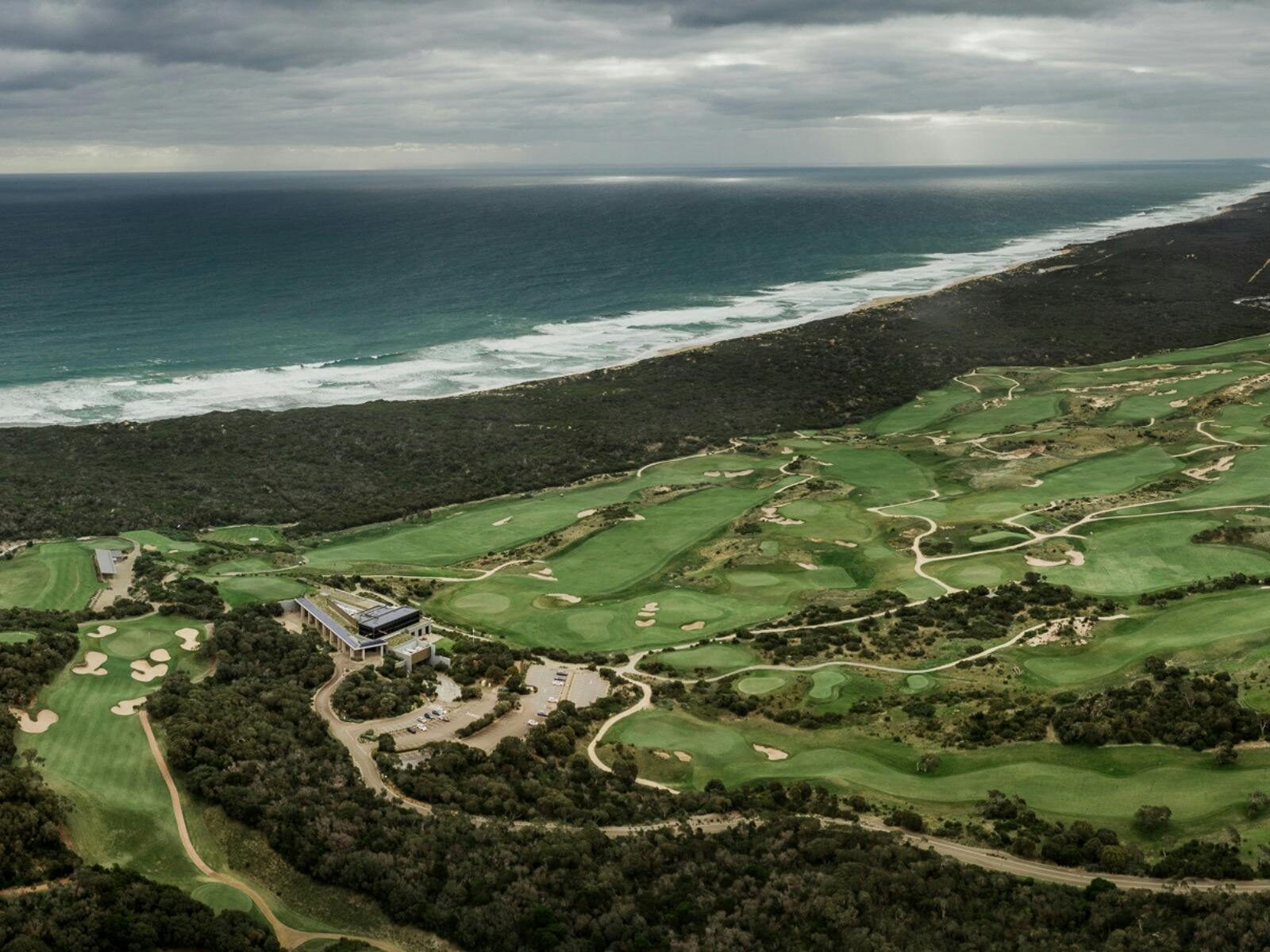 Aerial of The National Golf Club with fairways, greens, bunkers, and ocean backdrop.