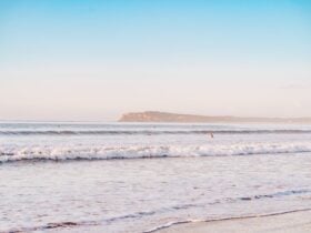 The soft waves rolling into shore at Thirteenth Beach with whitewash and a cliff in the background