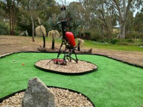 Mini golf green with a large imaginary creature sculpture in the middle.