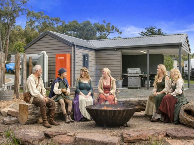 people dressed for a renfair sitting around fire
